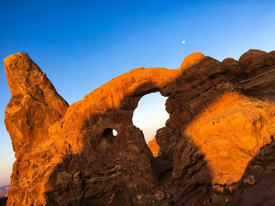 Turret Arch glowing orange at sunrise with the moon above — Arches National Park Utah fine art print