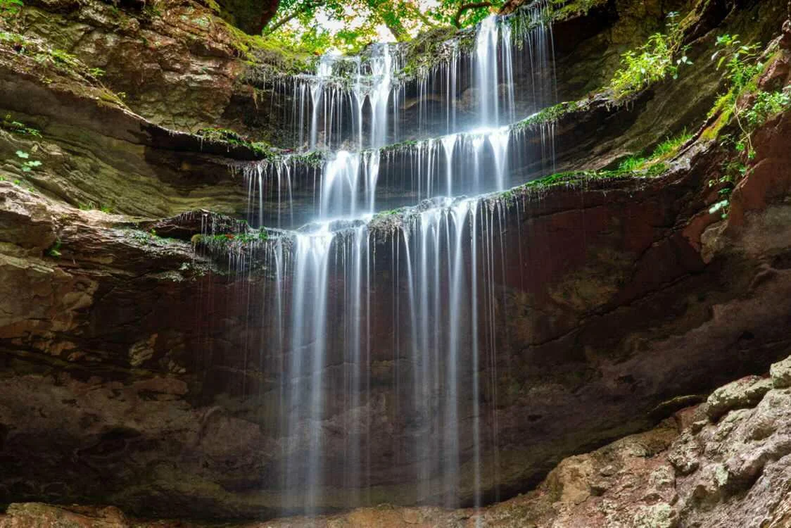 Tiered waterfall cascading over layered rock in an arched grotto at Lost Creek Falls — Tennessee fine art print
