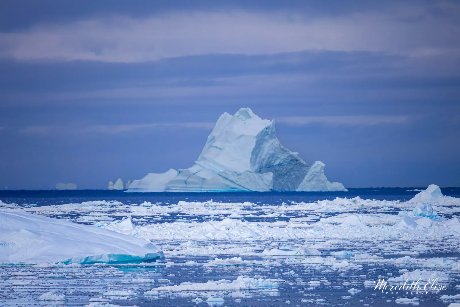 Towering iceberg on the horizon surrounded by scattered floating ice — Greenland fine art print
