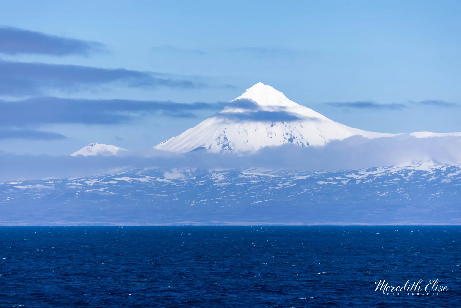 Snow-covered cone of Pogromni Volcano rising above the deep blue Bering Sea — Unimak Island Aleutian Islands Alaska fine art print