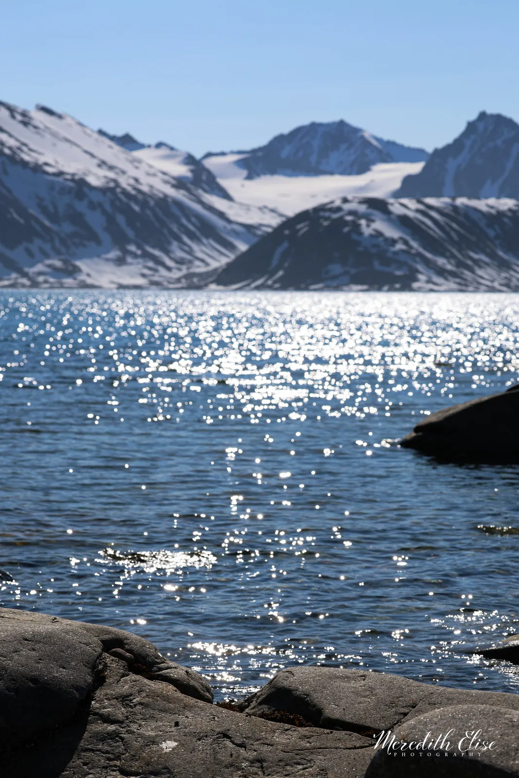 Sunlight sparkling across an Arctic fjord beneath snow-covered mountains — Svalbard Norway fine art print